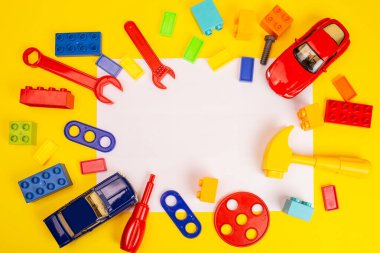 Renkli oyuncakların üst görünümü ve beyaz ve sarı arkaplan üzerine inşa araçları