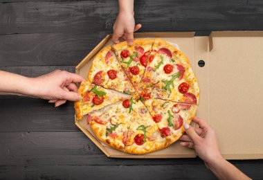 Domatesli, salamlı ve peynirli pizza dilimleri tutan insanların kısmi görüntüsü