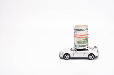 Beyaz arka planda oyuncak arabalı dolar banknotları