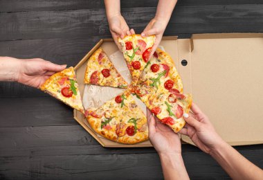 İnsanların ellerinde domatesli, salamlı ve peynirli pizza dilimleriyle kestikleri sahneler.  