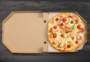 Domatesli pizza, salam ve peynir tahta masada kutuda. 