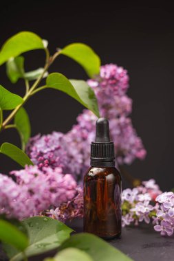 Parfüm şişesi ve çiçekler ahşap bir masada.