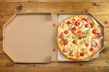 Domatesli, salamlı, peynirli, ahşap masada nefis pizzanın üst görüntüsü. 