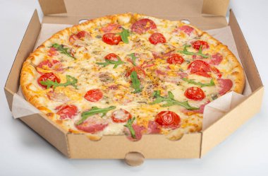 Beyaz arka planda domatesli, salamlı ve peynirli pizzanın yakın plan görüntüsü. 