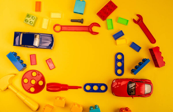 вид на красочные игрушки и строительные инструменты на белом и желтом фоне
