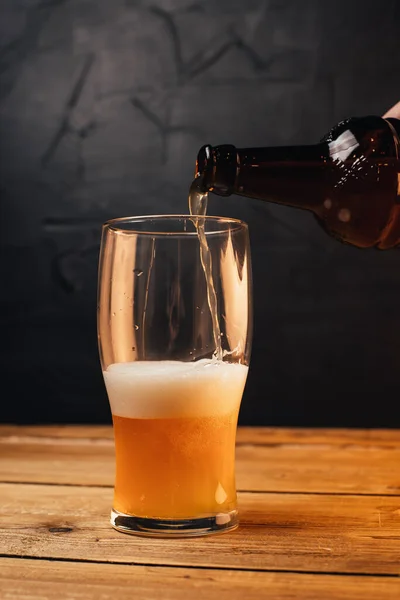 Teilansicht Einer Person Die Bier Aus Flasche Becher Auf Holztisch — Stockfoto