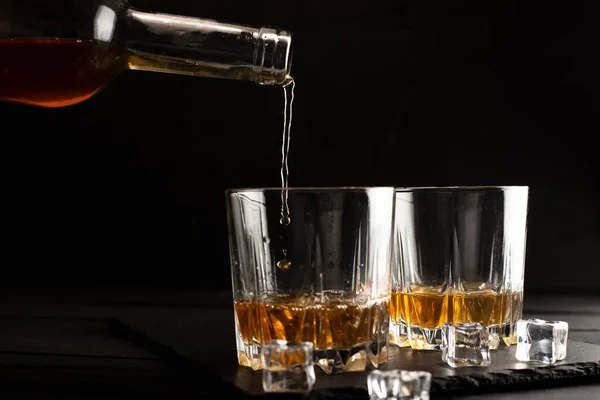 Widok Bliska Wylewania Whisky Butelki Szklanek Kostkami Lodu Ciemnym Drewnianym — Zdjęcie stockowe