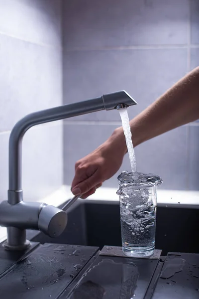 woman pouring water from the tap in the kitchen