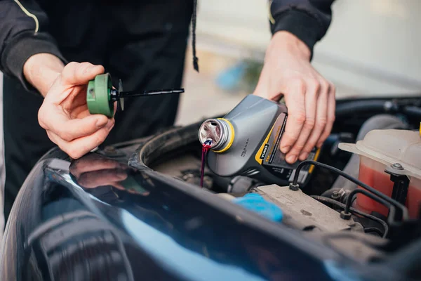 Mechanic tightening the valve steering fluid reservoir. Car mechanic exchanging steering system fluid.