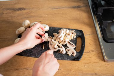 Mutfaktaki ahşap masada taze mantar keserken çekilmiş bir fotoğraf.