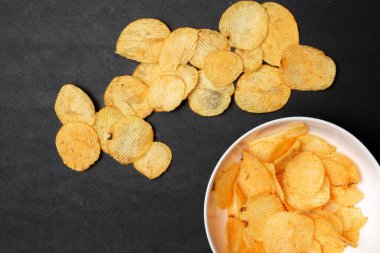 Siyah arka plandaki patates cipslerinin yakın plan görüntüsü. 