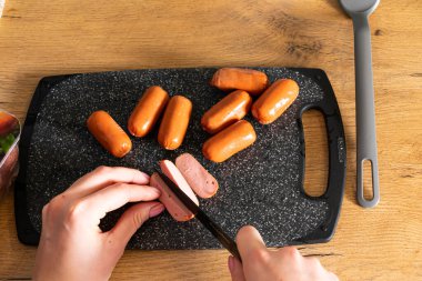 Kesme tahtasında sosis doğrayan kadının kısmi üst görüntüsü