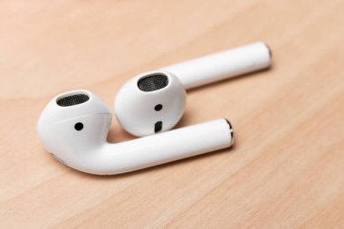 Ahşap yüzeydeki modern beyaz kulaklıkların yakın çekim görüntüsü