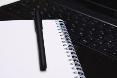 beyaz arkaplanda kalem olan dizüstü bilgisayar ve defter