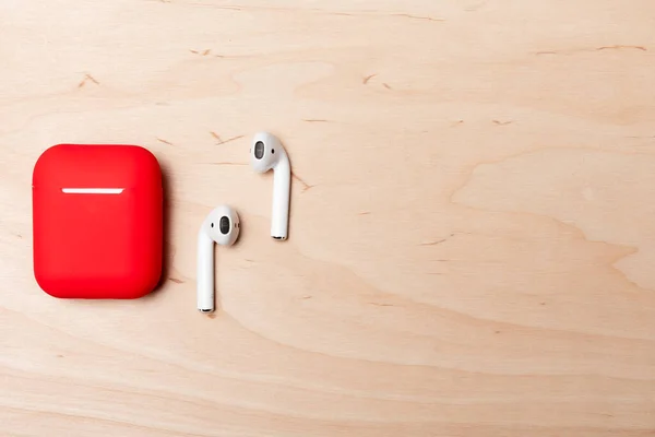 Nahaufnahme Moderner Weißer Ohrhörer Und Roter Behälter Auf Holzgrund — Stockfoto