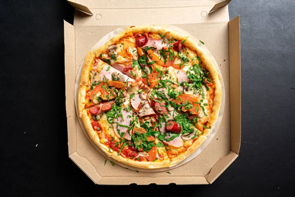 Siyah arka planda jambonlu, peynirli ve mantarlı lezzetli pizzanın üst görüntüsü.