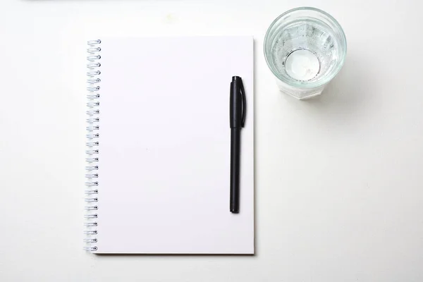 Σημειωματάριο Στυλό Και Ποτήρι Νερό Λευκό Φόντο — Φωτογραφία Αρχείου