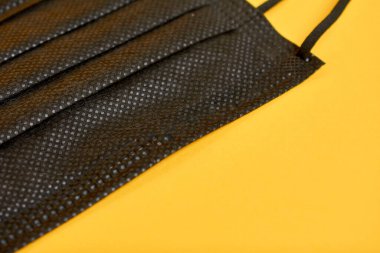 Sarı arka planda siyah tıbbi maskelerin yakın plan görüntüsü 