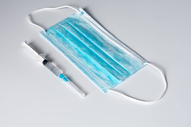 Gri arka planda tıbbi maske ve şırınga  