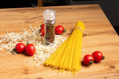 Domatesli ve ahşap masadaki baharatlı pişmemiş spagetti yakın plan görüntüsü.