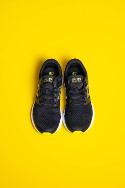 Parlak sarı arka planda şık siyah spor ayakkabılarının yakın plan görüntüsü