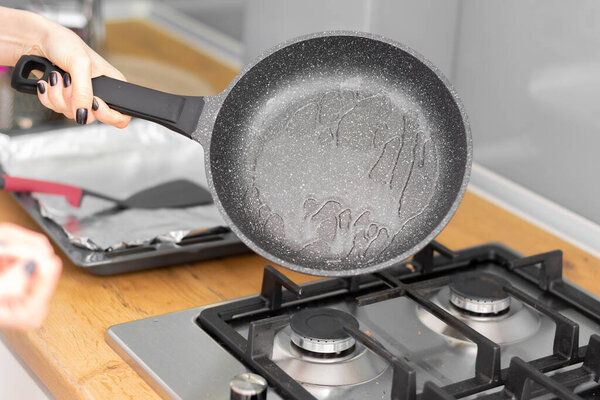 обрезанный снимок женщины, держащей сковородку с маслом и приготовления пищи на кухне