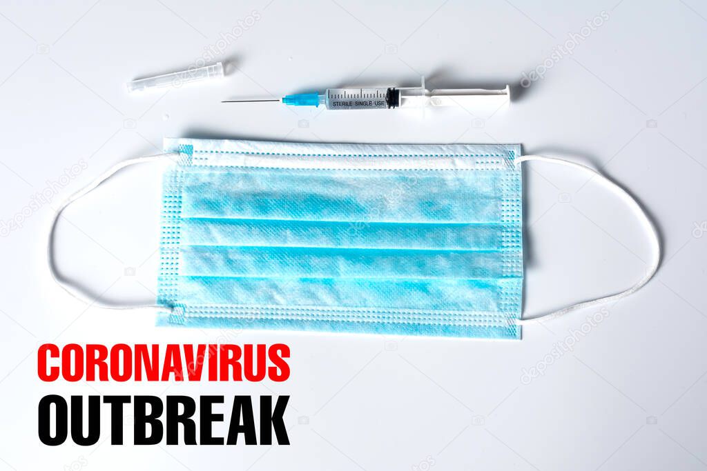top view of medical mask, syringe and coronavirus outbreak inscription on grey background  