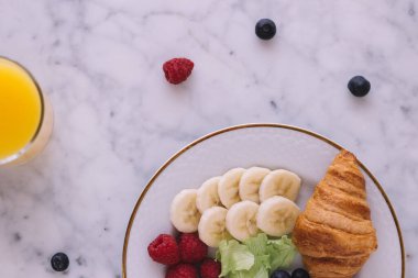 Muz, yabanmersini, ahududu ve kruvasan manzaralı sağlıklı bir kahvaltı.