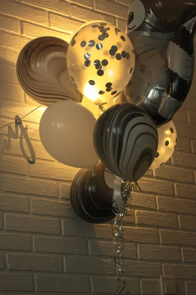Воздушные шары на день рождения: черно-белые шарики на фоне стены из белого кирпича — стоковое фото