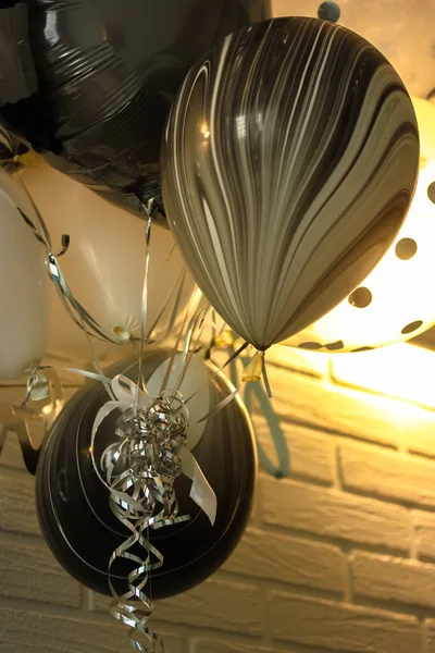 День рождения черно-белые воздушные шары на фоне стены из белого кирпича и серебряные нити — стоковое фото