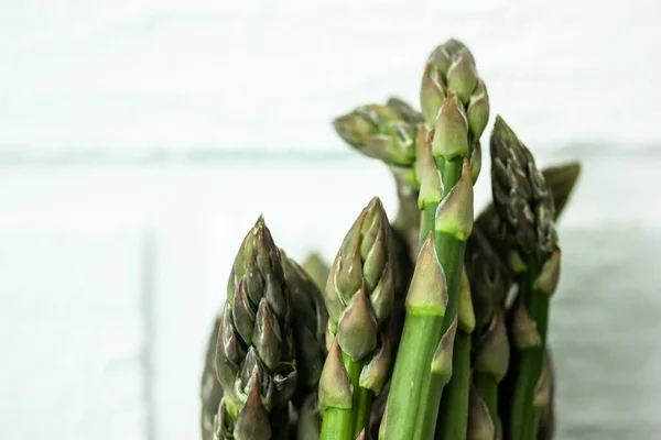 Asparagus. Fresh green close up asparagus on a light white clear background, white brick wall. — Stock Photo, Image