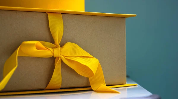 Scatola di cartone giallo con un fiocco con un regalo all'interno per un compleanno o un'altra festa — Foto Stock