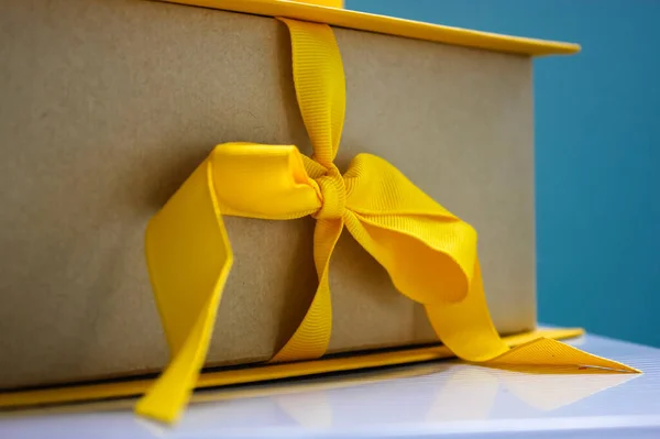 Scatola di cartone giallo con un fiocco con un regalo all'interno per un compleanno o un'altra festa — Foto Stock