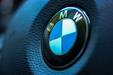 Arabada oturan ve direksiyonu tutan kişi: BMW logosu.