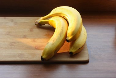 Yazın mutfak masasının ahşap yüzeyinde olgun sarı muzlar.