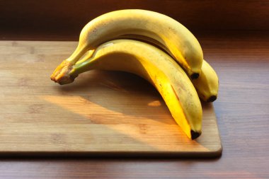 Yazın mutfak masasının ahşap yüzeyinde olgun sarı muzlar.