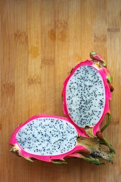 Ripe juicy bright pink dragonfly on the wooden surface of the worktop on kitchen, exotic summer fruits