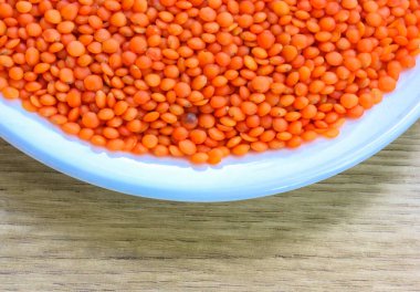 Yuvarlak beyaz tabakta kırmızı mercimek: sağlıklı bir diyet için doğal yemek malzemeleri