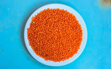 Yuvarlak beyaz tabakta kırmızı mercimek: sağlıklı bir diyet için doğal yemek malzemeleri