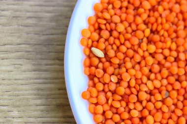 Yuvarlak beyaz tabakta kırmızı mercimek: sağlıklı bir diyet için doğal yemek malzemeleri