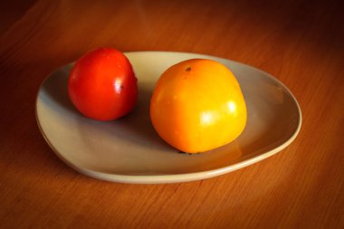 Mutfak masasında, gri tabakta kırmızı ve sarı olgun domatesler. Yüksek kalite fotoğraf