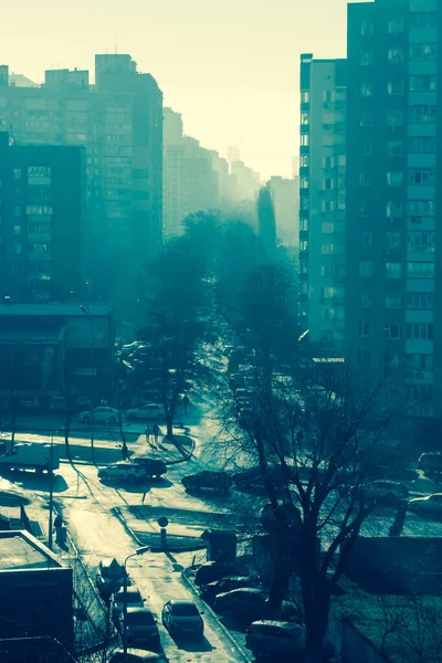 Vista da janela em edifícios de vários andares e da rua com tráfego pesado, manhã de outono ensolarada e gelada na cidade. — Fotografia de Stock
