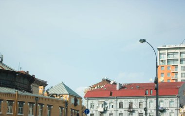 Kyiv şehir merkezindeki eski evlerin çatıları ve ufuktaki modern gökdelenler, sıcak güneşli bir günde mavi gökyüzü..
