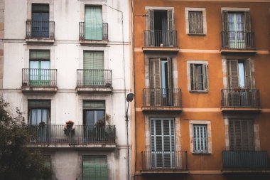 Barselona, İspanya 2 Mayıs 2024 Avrupa mimarisi, balkonları ve renkli cepheleri var. Çarpıcı bir bina manzarası, kapalı panjurlu bazı pencereler. Evin önü görünüyor. İspanyol sokağı.