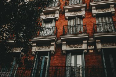 Balkonları ve tuğlaları olan tarihi bir bina. Avrupa 'da bir şehirde balkonların, dekoratif detayların ve mimari tasarımın yer aldığı güzel bir tuğla binanın yakın çekimi..