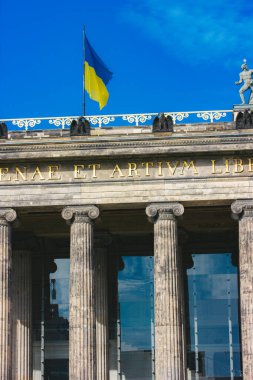 Berlin, Almanya 2 Ekim 2022 Ukrayna bayrağı gururla bir klasik mimari binanın tepesinde dalgalanıyor. Ukrayna bayrağının dalgalandığı canlı mavi gökyüzünün altındaki tarihi bir binanın detaylı bir görüntüsü..