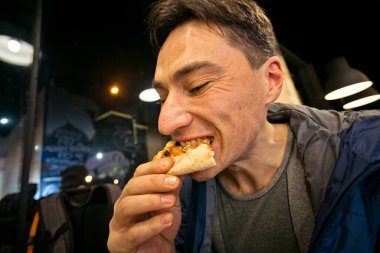 Pizza yiyen adam. - Kafede. Elinde bir dilim pizza var, yakın plan..
