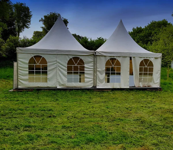 Two big white tents for events in the woods on a festival meadow