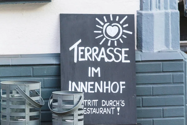 Slate in front of a restaurant with a caption in German \