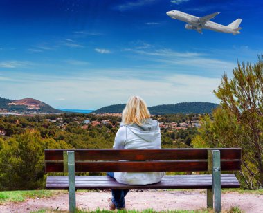 Woman sitting on a bench with panoramic view over Paguera towards bay of Palma, Mallorca in Spain. clipart